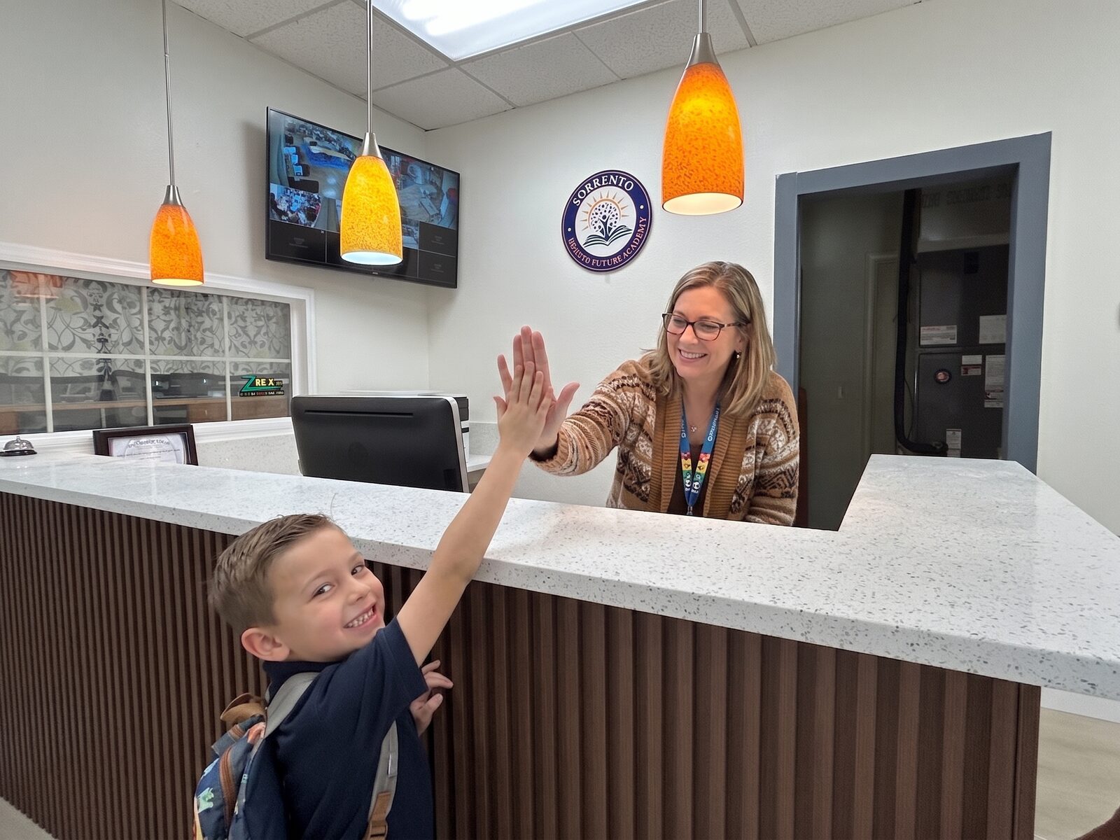 Sorrento Bright Future Academy staff welcoming a student with a high five at the front desk